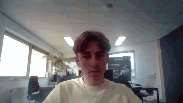a man in a white shirt is sitting in front of a window with a sign that says board on it