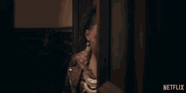 a woman standing in a dark room with a netflix logo on the bottom right