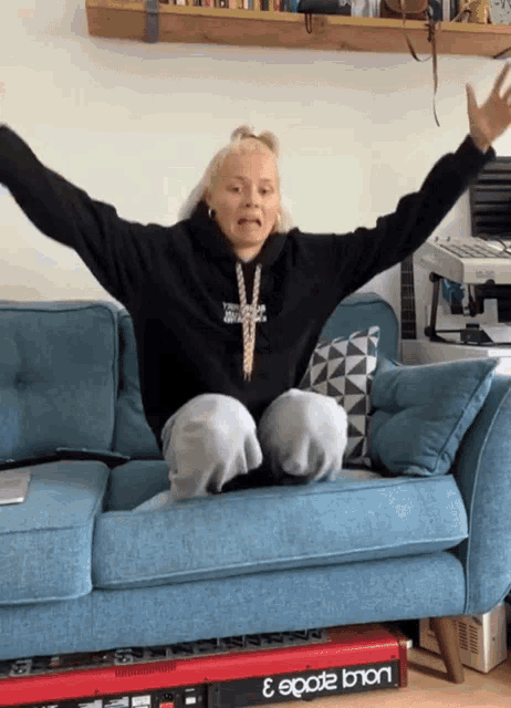 a woman sits on a blue couch with her arms outstretched in front of an eppad 3
