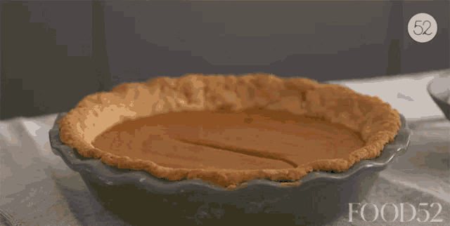 a pumpkin pie with a slice taken out of it sits on a table with food52 written on the bottom of the pie