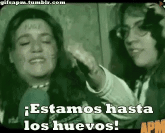 a woman is talking into a microphone while another woman holds her hand up and says estamos hasta los huevos !
