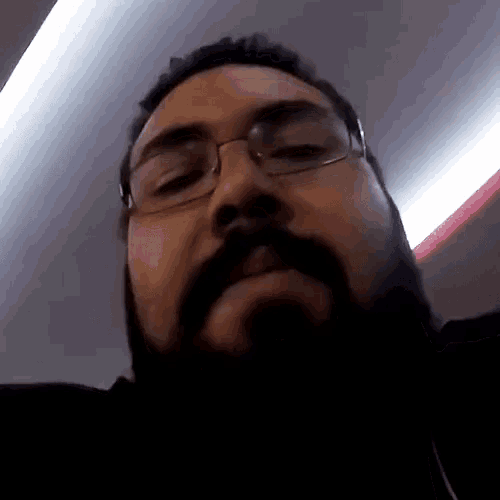 a man with glasses and a beard looks down at the camera