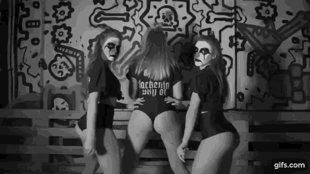 three women are dancing in front of a wall with graffiti on it .