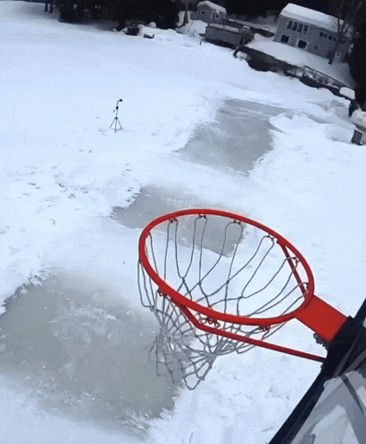 a basketball hoop is in the snow near a frozen lake