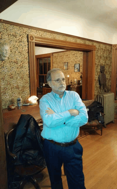 a man with his arms crossed standing in a room