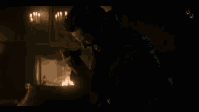 a man sitting in front of a fireplace with candles in the background