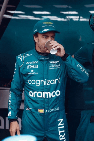 a man in a racing suit with the word cognizant on it drinks from a cup