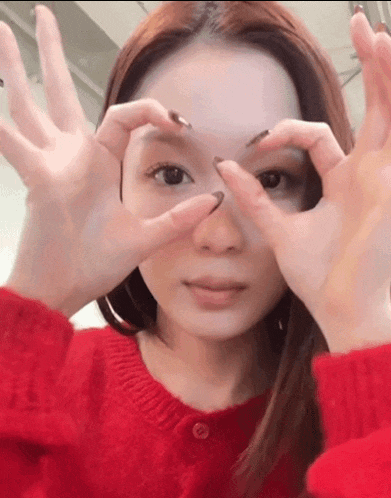 a woman in a red sweater is making a face with her hands