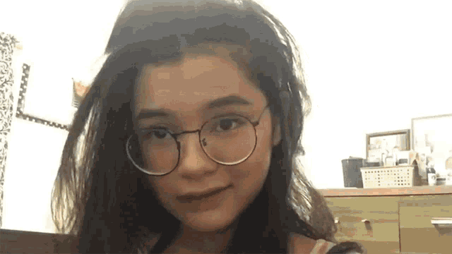 a girl wearing glasses looks at the camera with a smile on her face