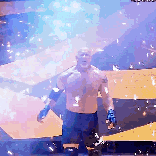 a man without a shirt is standing on a stage with feathers flying around him