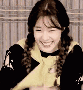 a young woman with braids is smiling and holding a yellow object .