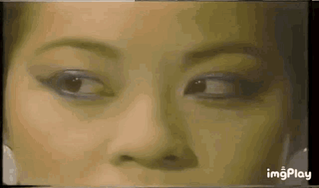 a close up of a woman 's face with a blurred background and the words imgplay on the bottom .