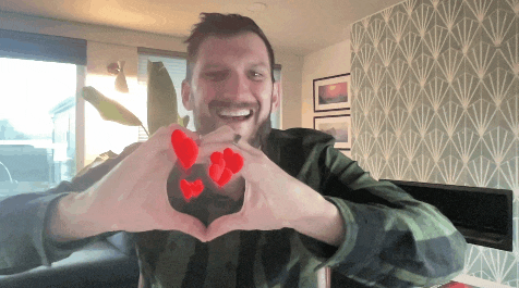 a man in a plaid shirt makes a heart with his hands