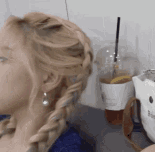 a woman with a braided hairstyle is sitting next to a cup of coffee .