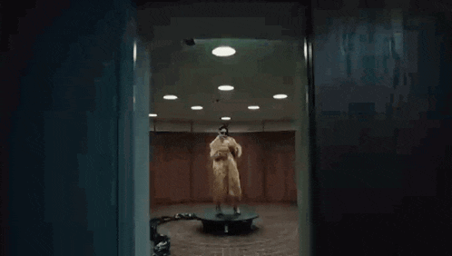 a person in a fur coat is standing on a circular platform in a dark room .