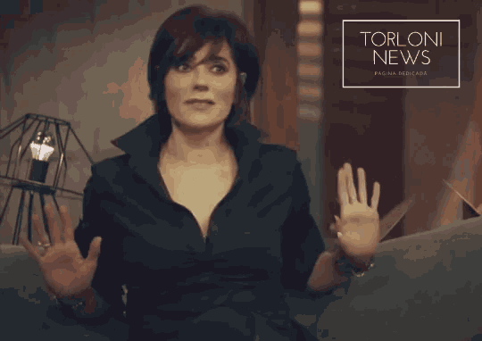 a woman sitting on a couch with her arms outstretched in front of a torloni news banner