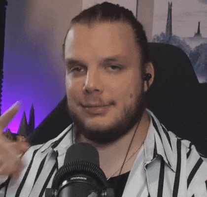 a man with a beard and headphones is sitting in front of a microphone .