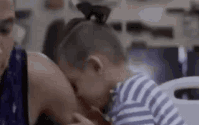 a little girl is laying on a woman 's lap in a hospital bed .