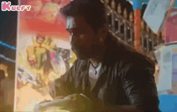 a man is sitting at a table in front of a wall with a painting on it .