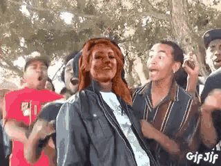 a group of people are dancing in a park and a woman is standing in the middle .
