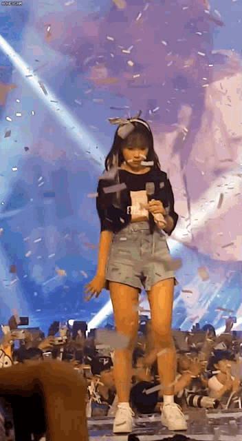 a girl is standing on a stage with a microphone in her hand
