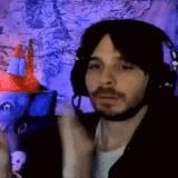a man with a beard wearing headphones and a microphone is giving a thumbs up .