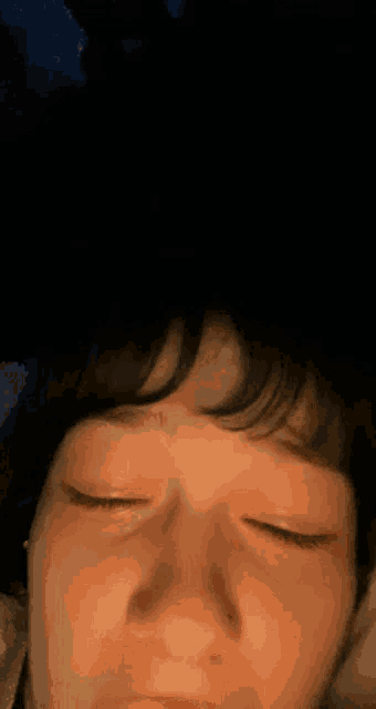 a close up of a person 's face with their eyes closed and their hand on their forehead .
