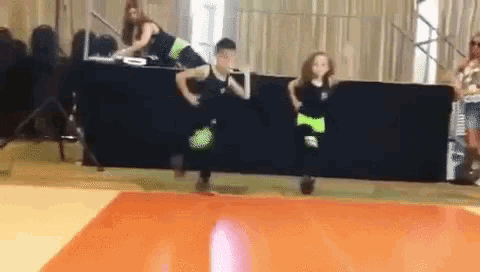 a boy and a girl are dancing on a stage in front of a crowd .