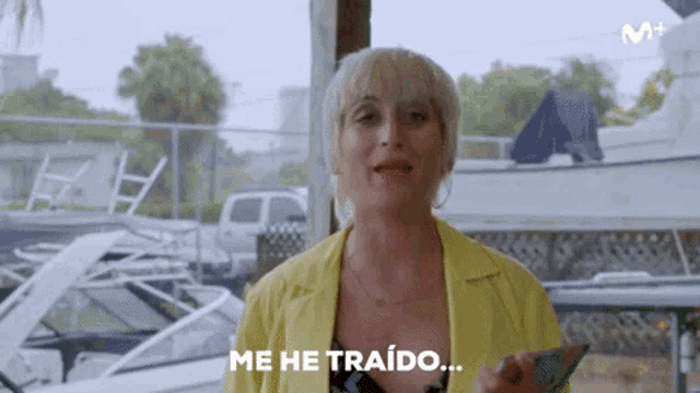 a woman in a yellow jacket is holding a cell phone and says me he traido ..