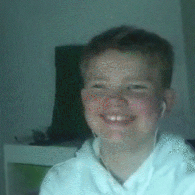 a young boy wearing headphones and a white shirt smiles for the camera