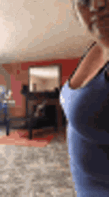 a woman wearing a blue tank top is standing in a living room .