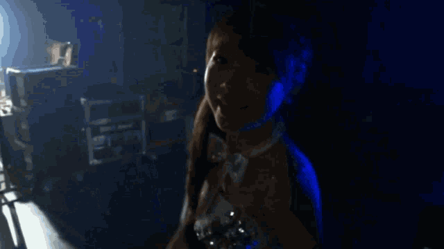 a woman in a white dress is standing in a dark room with her arms outstretched