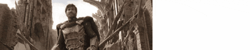 a black and white photo of a man in armor standing in front of a building