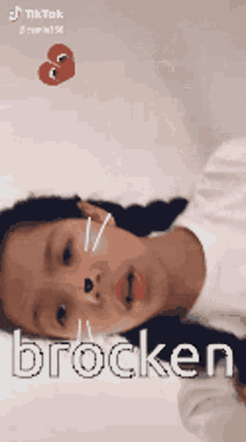a little girl is laying down with the word brocken on her face