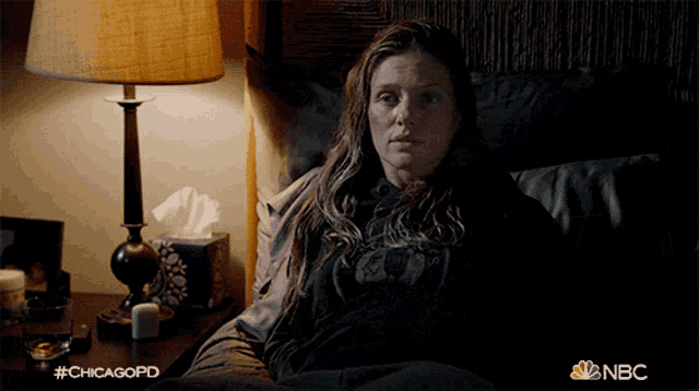 a woman is laying in bed with a lamp and a box of tissues and the hashtag #chicagopd
