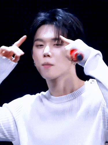 a man in a white sweater is making a peace sign with his fingers