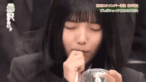 a girl with a straw in her mouth is drinking from a cup .