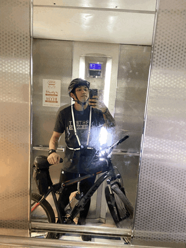 a man taking a picture of himself in an elevator with a sign that says myh