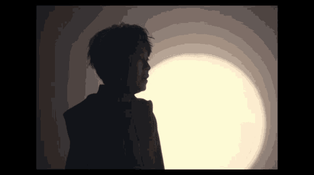 a silhouette of a person standing in front of a yellow light