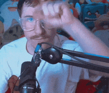 a man with glasses and a mustache is in front of a microphone .