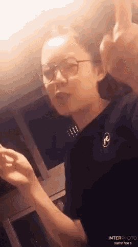 a woman wearing glasses and a black shirt has the word interphoto on her shirt