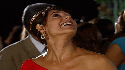 a woman in a red one shoulder dress is smiling and looking up