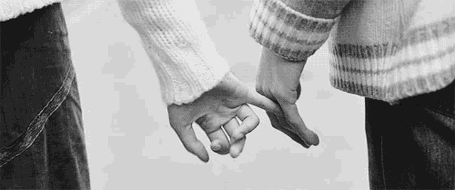 two people are holding hands in a black and white photo .