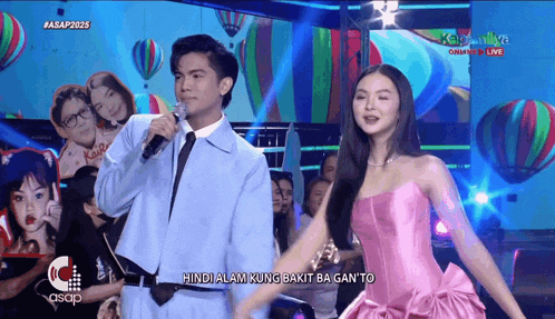 a man in a blue suit and tie stands next to a woman in a pink dress