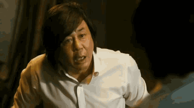 a man in a white shirt is making a funny face while talking to another man .