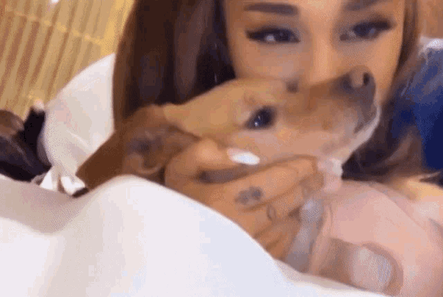 a woman with a tattoo on her finger is holding a small dog