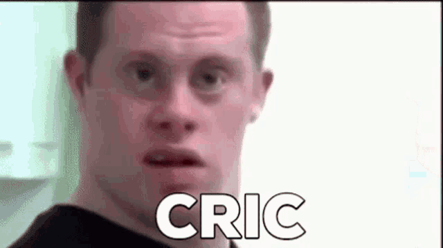 a man with down syndrome is making a funny face with the word cric written on it .