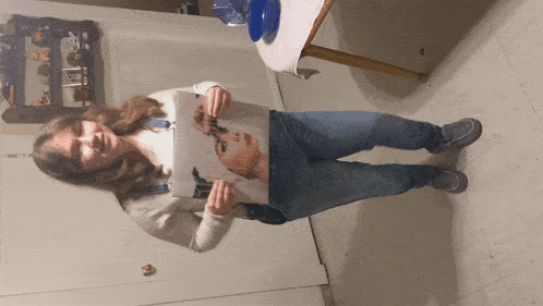 a woman is holding a painting of a woman 's face in her hands