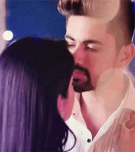 a man with a beard kissing a woman on the forehead
