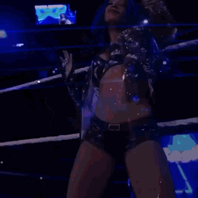 a woman with blue hair is standing in a wrestling ring with a sign that says sasha banks